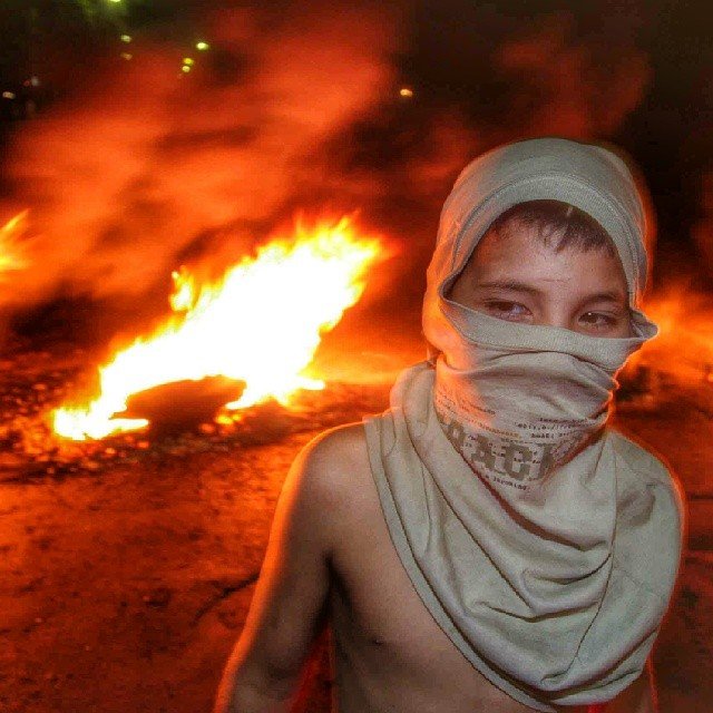 Joven con el rostro cubierto durante una protesta